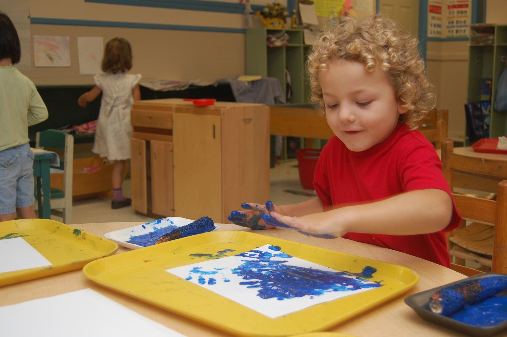 Boy fingerpaints with blue paint.