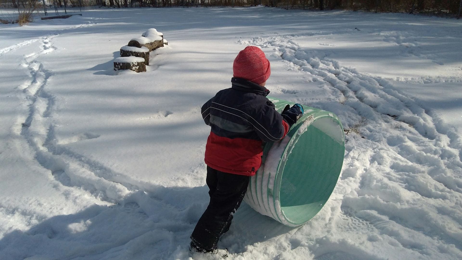 Boy pushes makes a track in the snow with a tunnel.